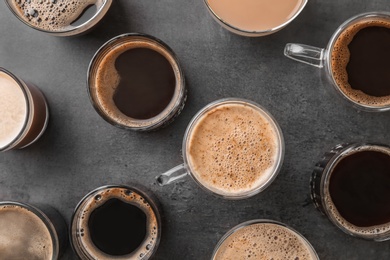 Many cups of different aromatic hot coffee on grey background, top view