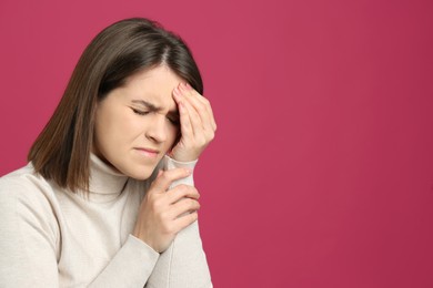 Photo of Young woman suffering from migraine on crimson background. Space for text