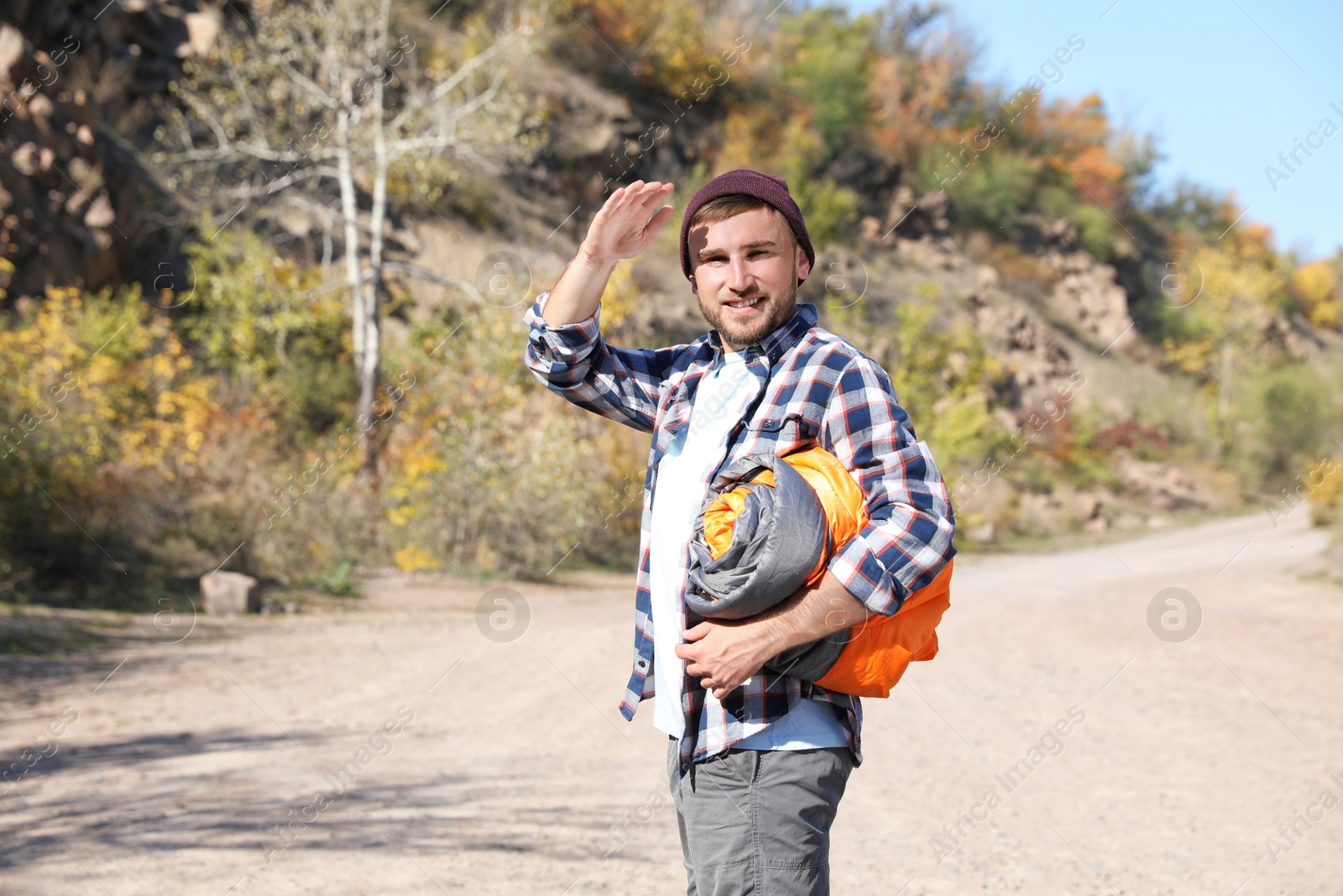 Photo of Young male camper with sleeping bag in wilderness