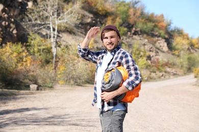 Young male camper with sleeping bag in wilderness