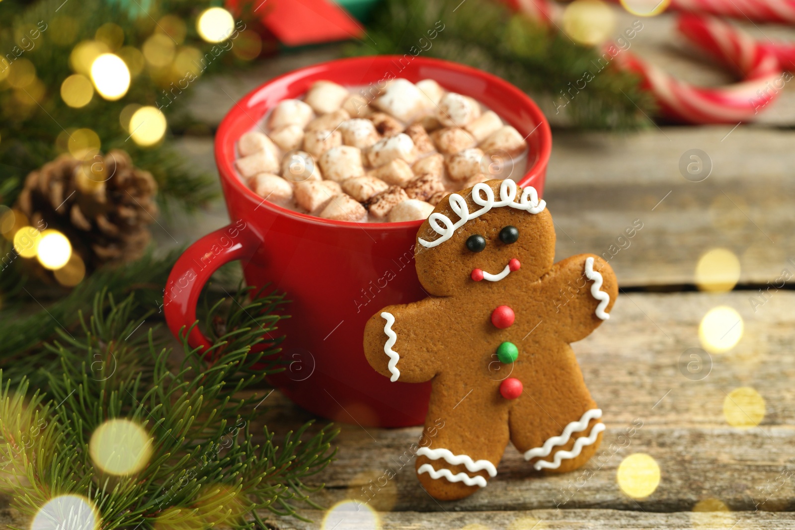 Photo of Tasty gingerbread man cookie and cocoa with marshmallows on wooden table, closeup