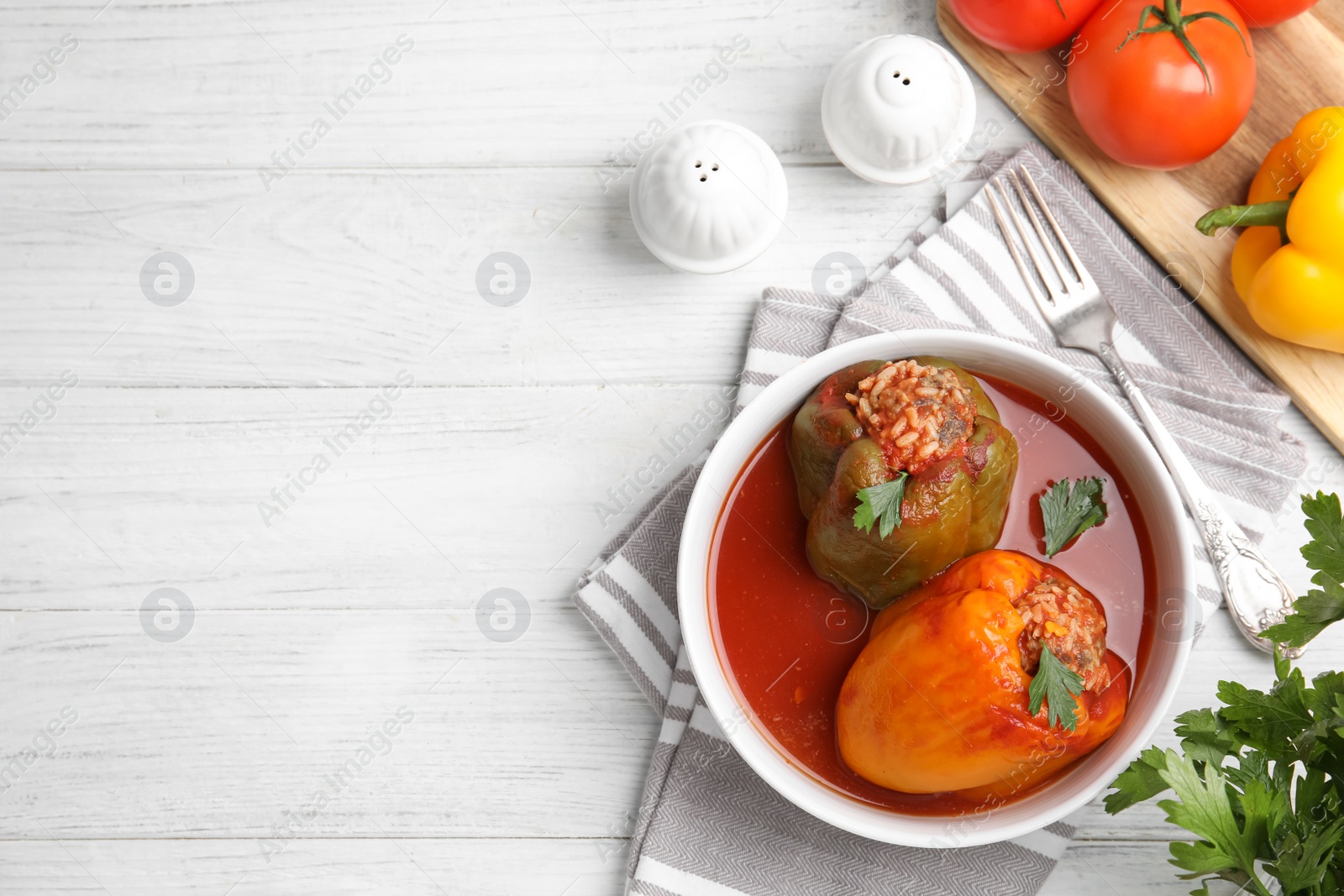 Photo of Delicious stuffed peppers served on white wooden table, flat lay. Space for text