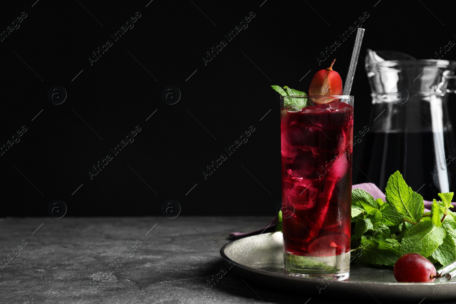 Photo of Delicious grape soda water with mint on grey table, space for text. Refreshing drink