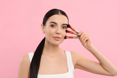 Photo of Beautiful woman with different makeup brushes on pink background