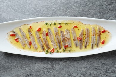 Photo of Tasty pickled anchovies with spices on gray table, top view