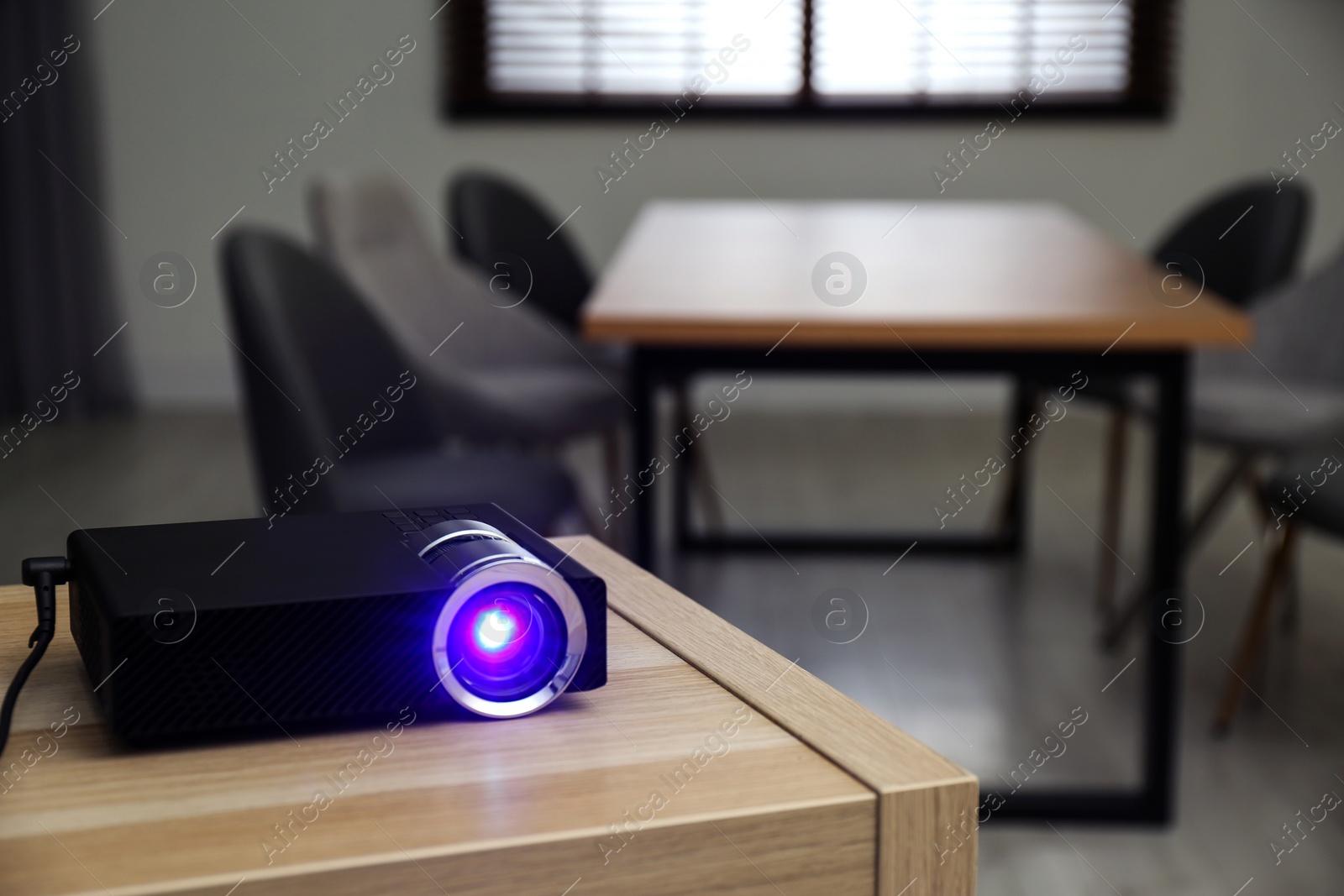 Photo of Modern video projector on wooden table in conference room. Space for text