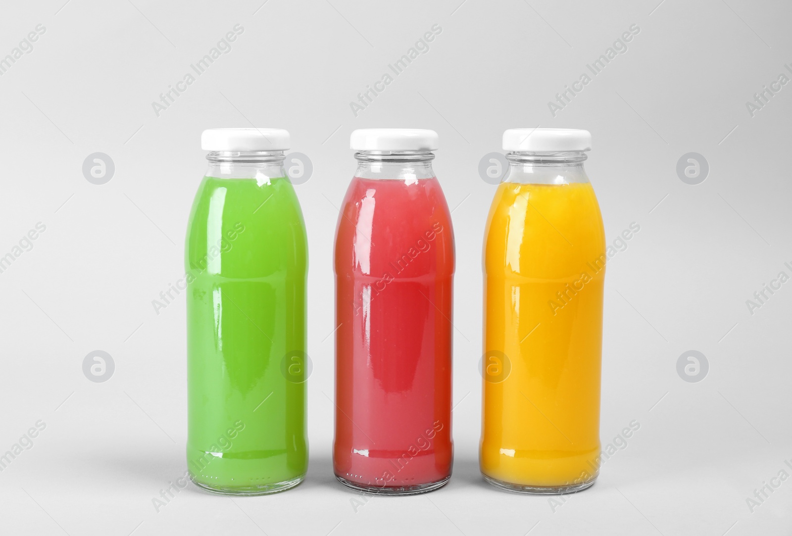 Photo of Bottles with delicious colorful juices on light background