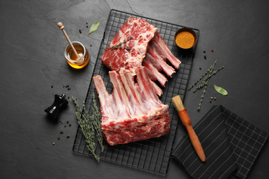 Raw ribs with thyme and pepper on black table, flat lay