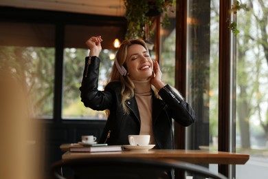 Young woman with headphones listening to music in cafe