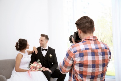 Professional photographer taking photo of wedding couple in studio