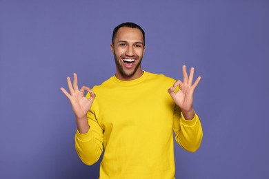 Happy African American man showing ok gesture on purple background