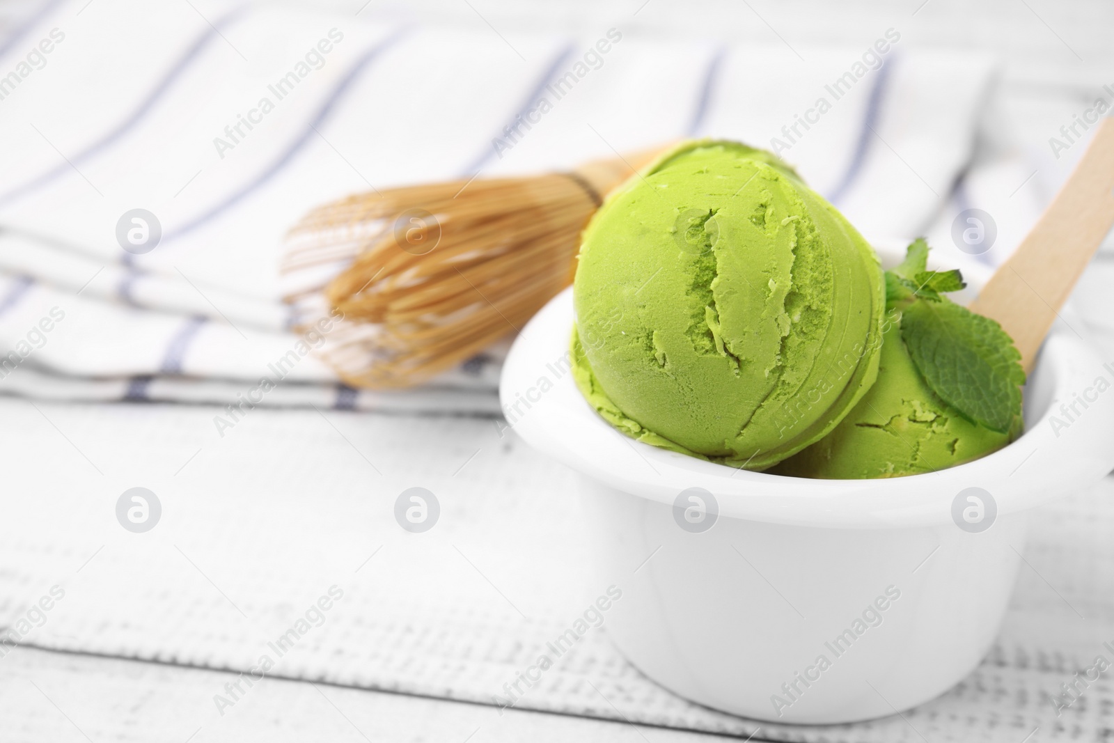 Photo of Tasty matcha ice cream in bowl on white wooden table. Space for text