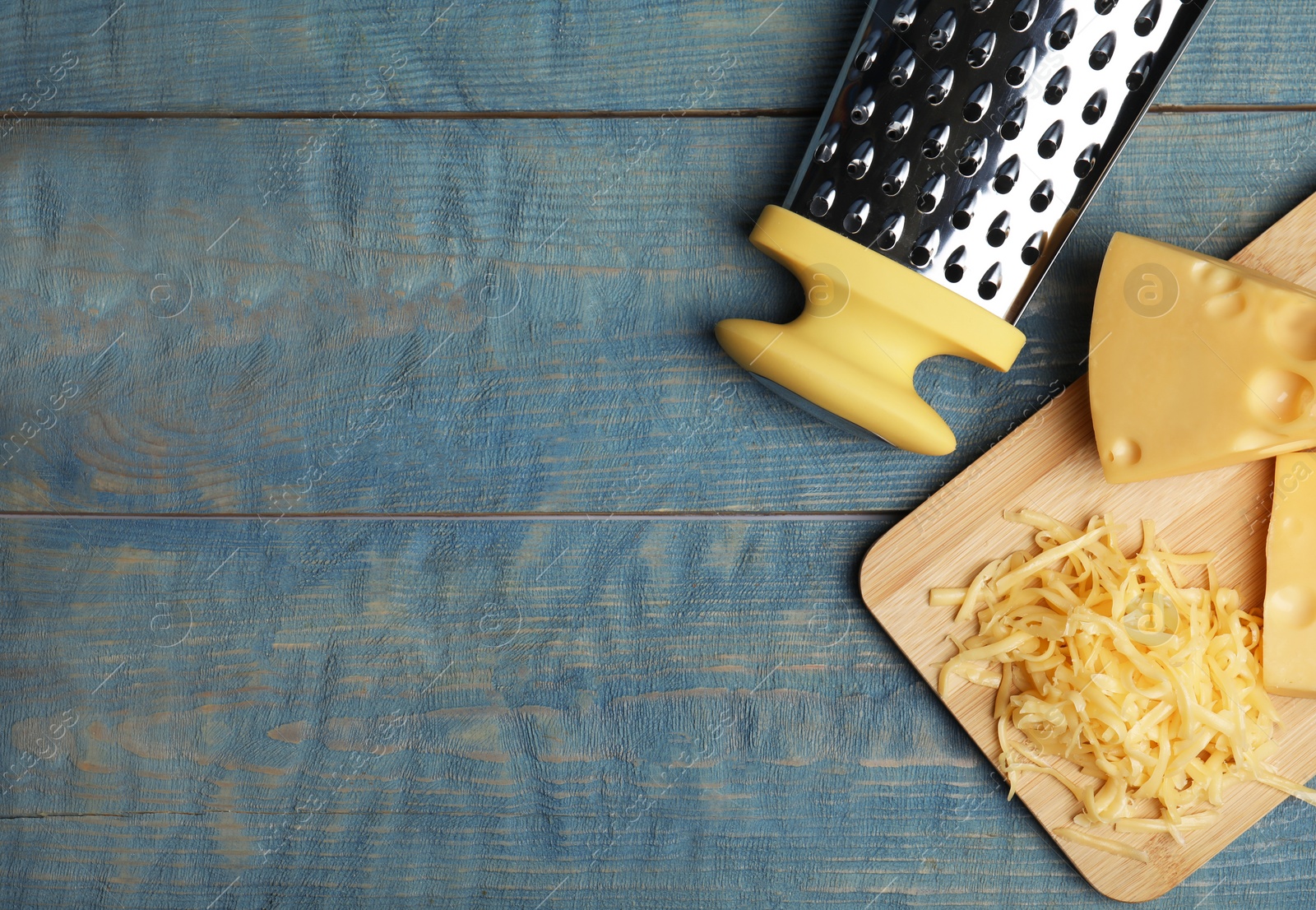 Photo of Tasty grated cheese on blue wooden table, flat lay. Space for text