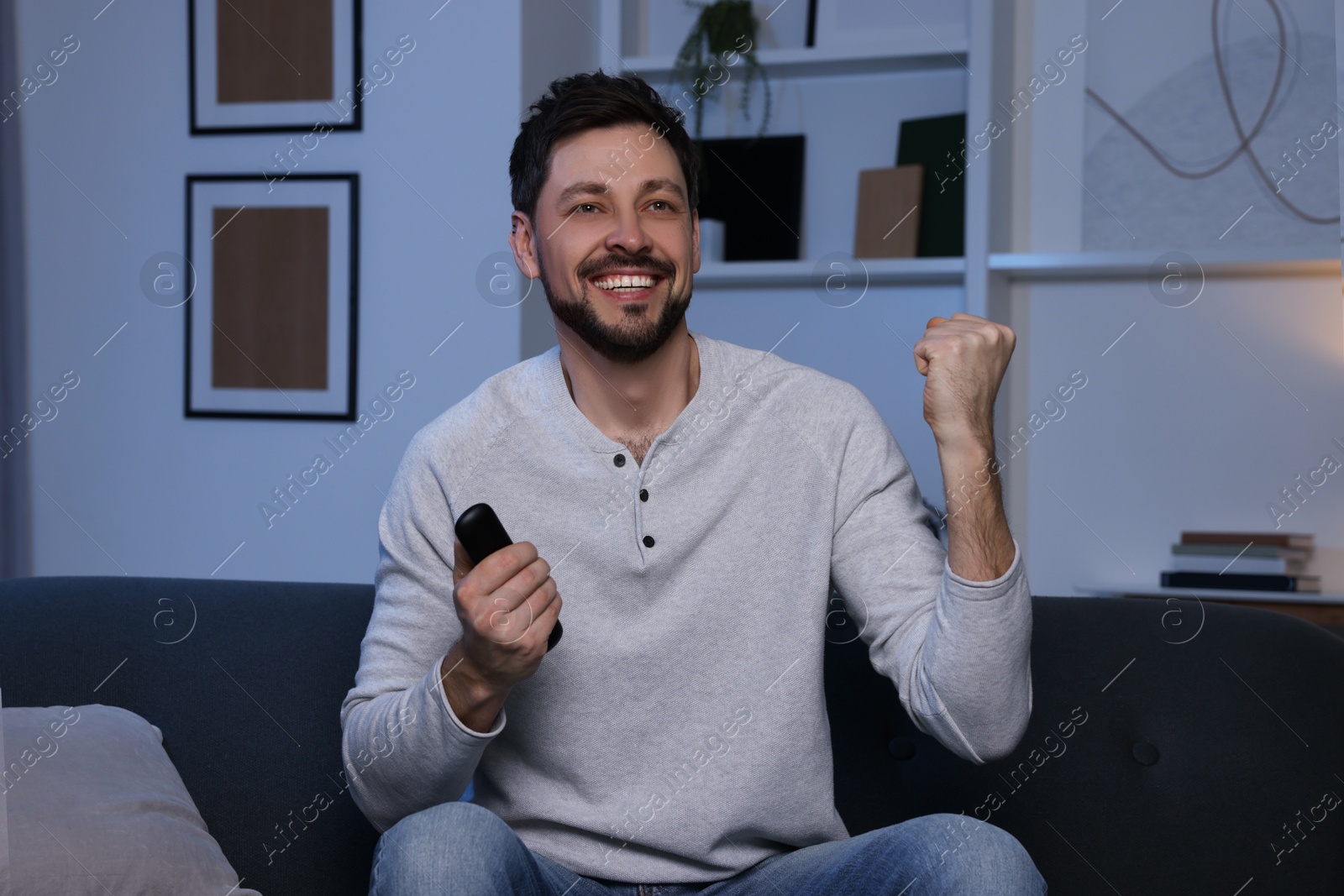 Photo of Happy man watching TV on sofa at home