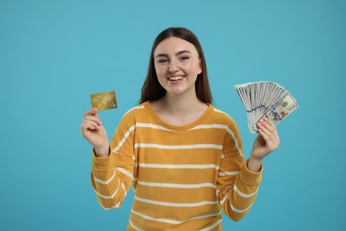 Happy woman with credit card and dollar banknotes on light blue background