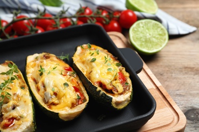 Photo of Baked stuffed zucchinis on wooden table, closeup