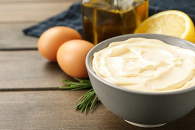 Photo of Bowl with fresh mayonnaise and ingredients on wooden table, closeup. Space for text