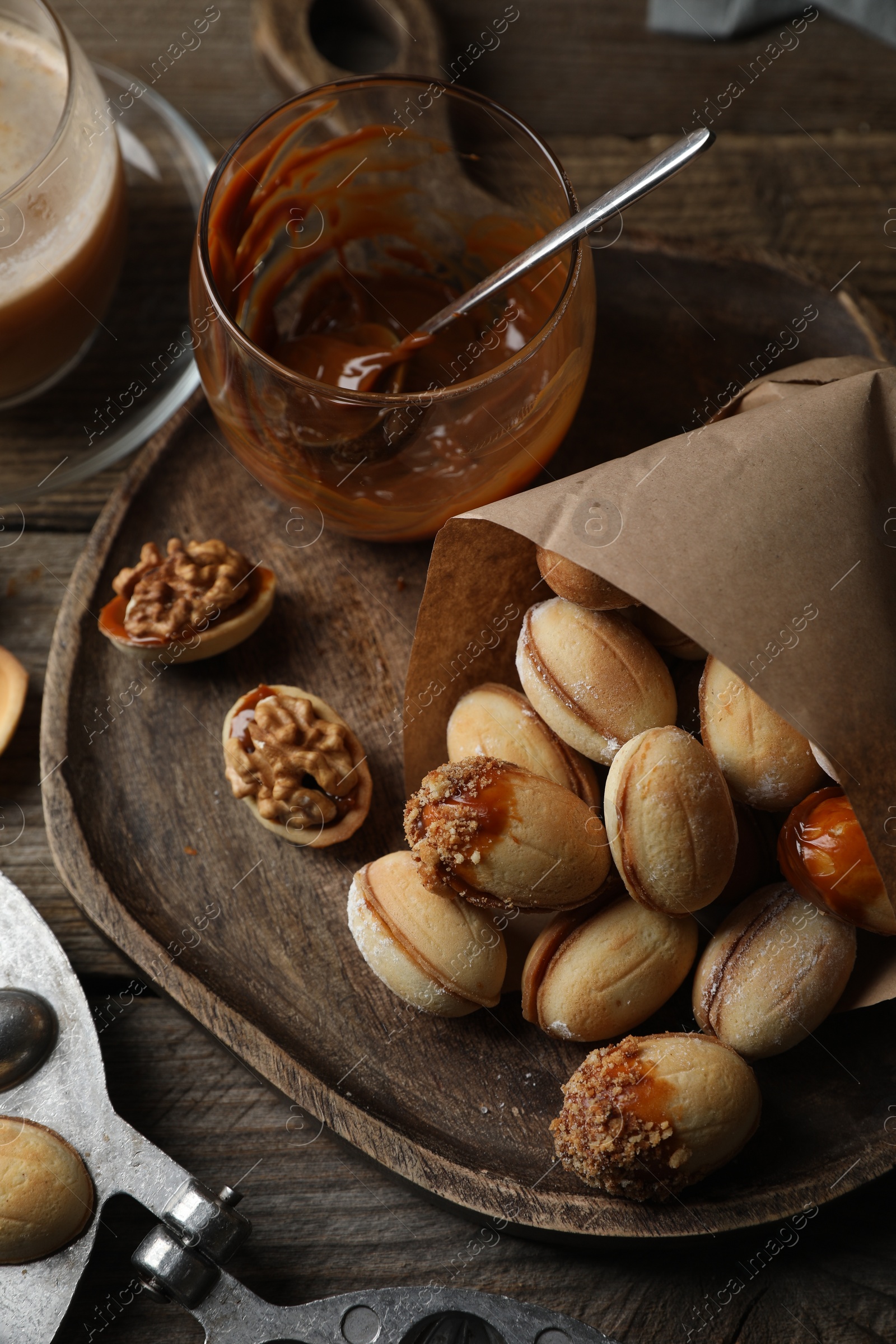 Photo of Freshly baked homemade walnut shaped cookies and boiled condensed milk on wooden table