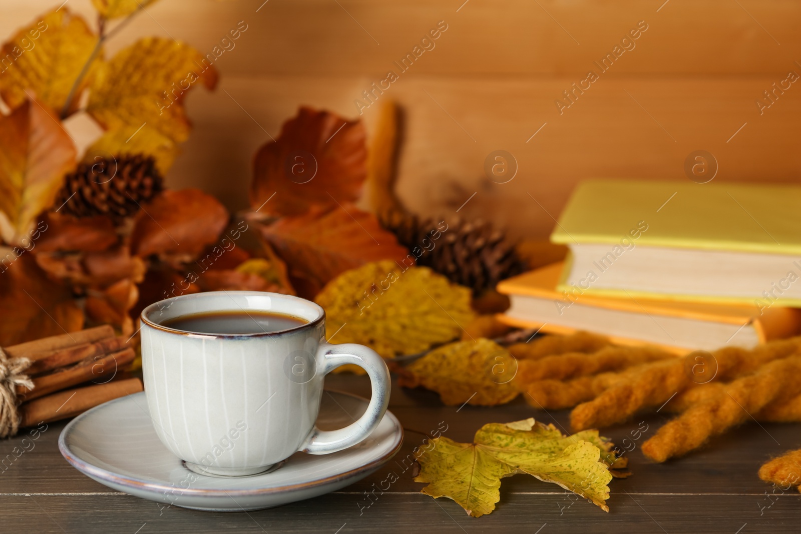 Photo of Composition with cup of hot coffee and autumn leaves on wooden table. Space for text