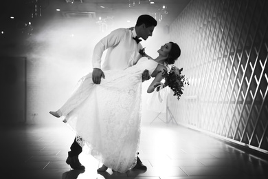 Happy newlywed couple dancing together in festive hall