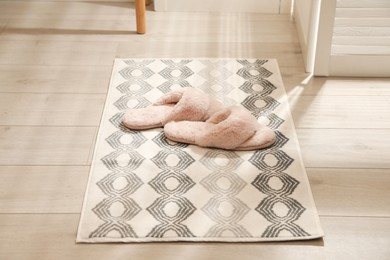 New stylish bath mat with fluffy slippers on floor indoors