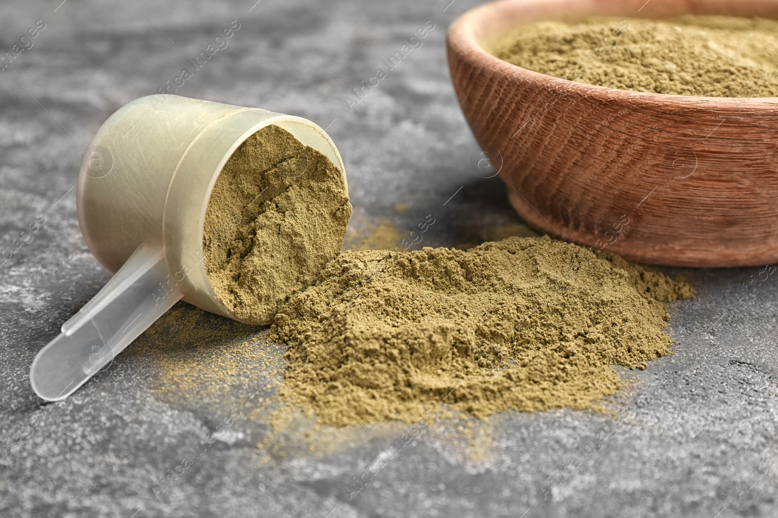 Photo of Measuring spoon and bowl with hemp protein powder on table