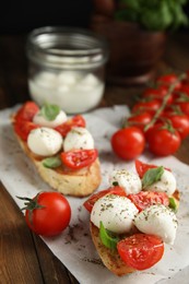 Photo of Delicious sandwiches with mozzarella, fresh tomatoes and basil on wooden table 