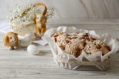 Photo of Delicious Italian Easter dove cake (traditional Colomba di Pasqua) and decorated eggs on white wooden table, space for text