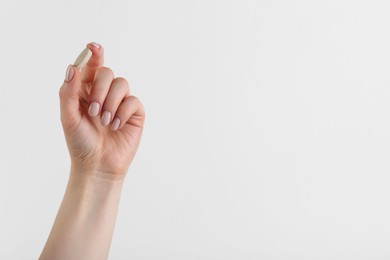 Photo of Woman holding vitamin pill on white background, closeup with space for text. Health supplement