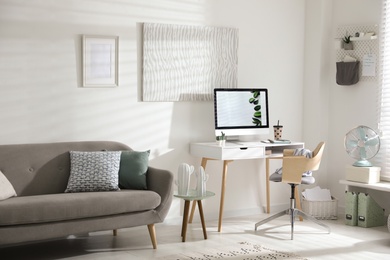 Photo of Comfortable office chair near desk with modern computer indoors