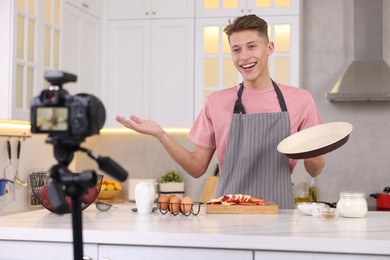 Photo of Smiling food blogger explaining something while recording video in kitchen