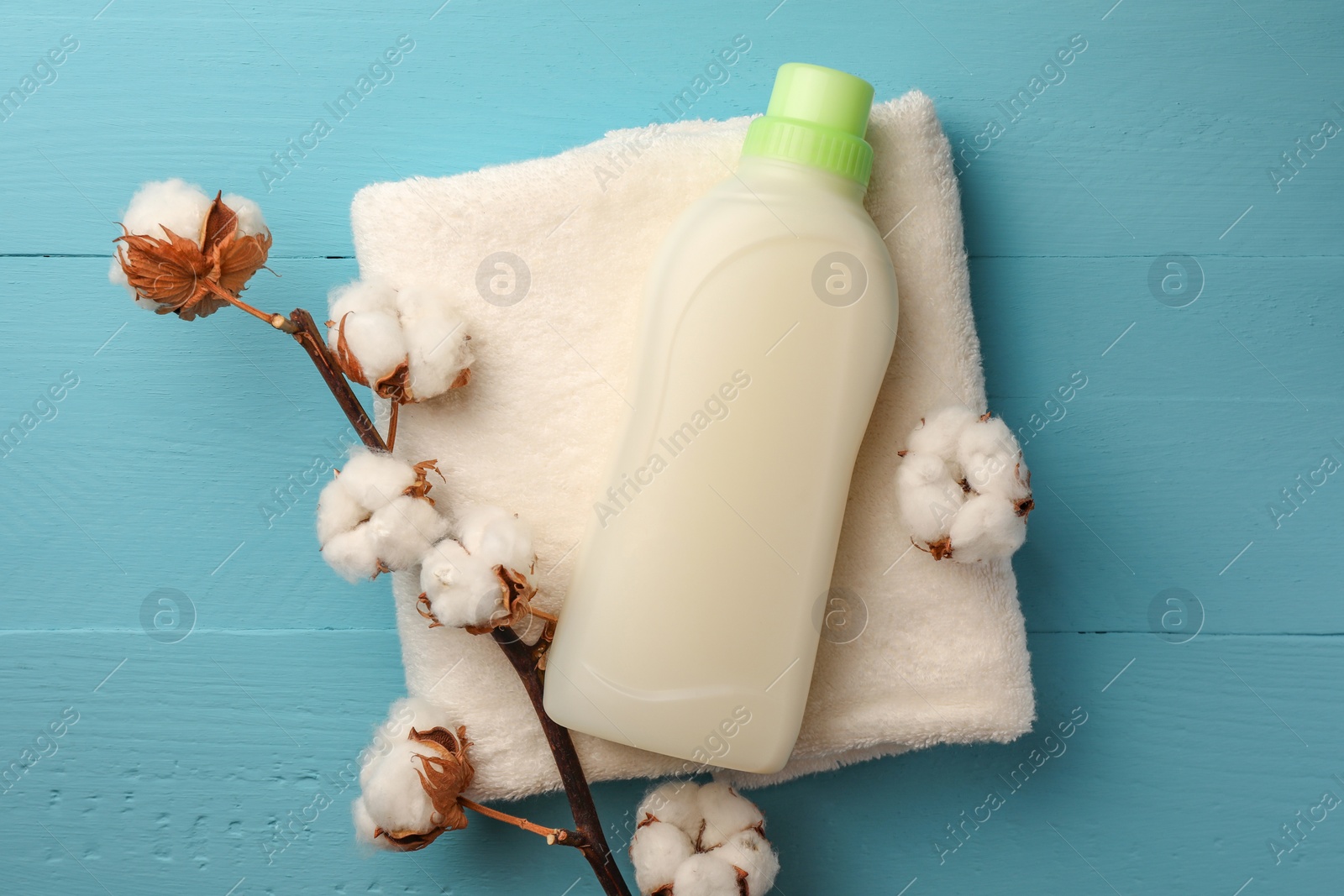 Bottle of fabric softener, terry towel and cotton flowers on light blue wooden table, flat lay Photo of Bottle of fabric softener, terry towel and cotton flowers on light blue wooden table, flat lay