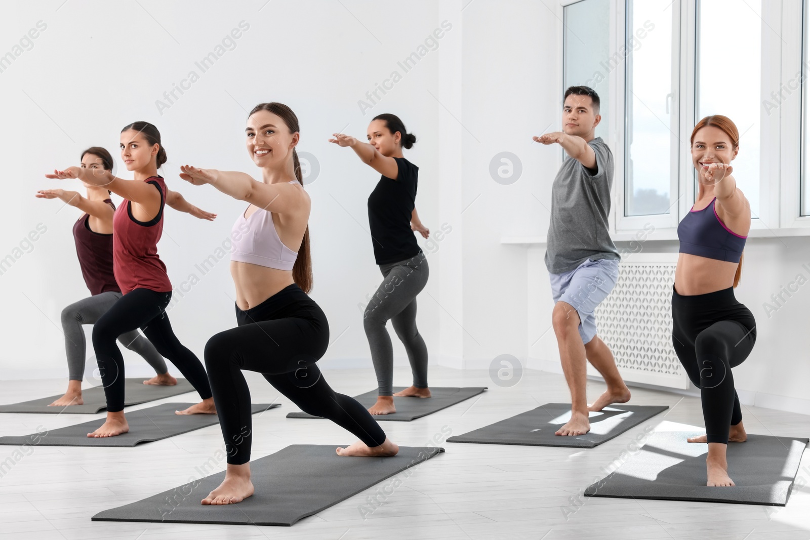 Photo of Group of people practicing yoga on mats indoors