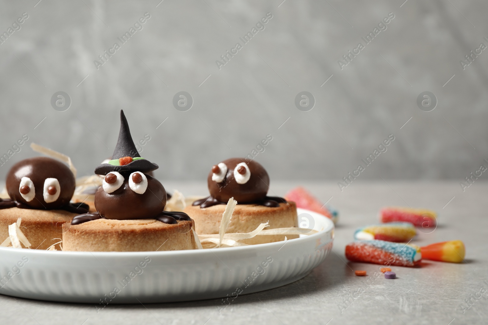 Photo of Delicious biscuits with chocolate spiders on light grey table. Halloween celebration