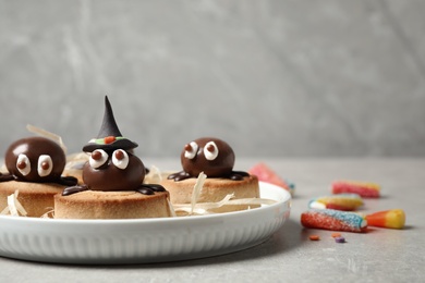 Delicious biscuits with chocolate spiders on light grey table. Halloween celebration