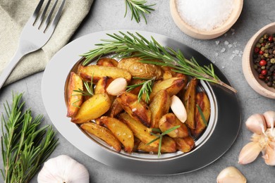 Tasty baked potato and aromatic rosemary served on grey textured table, flat lay