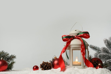 Photo of Decorative lantern and Christmas decor on snow against light grey background. Space for text