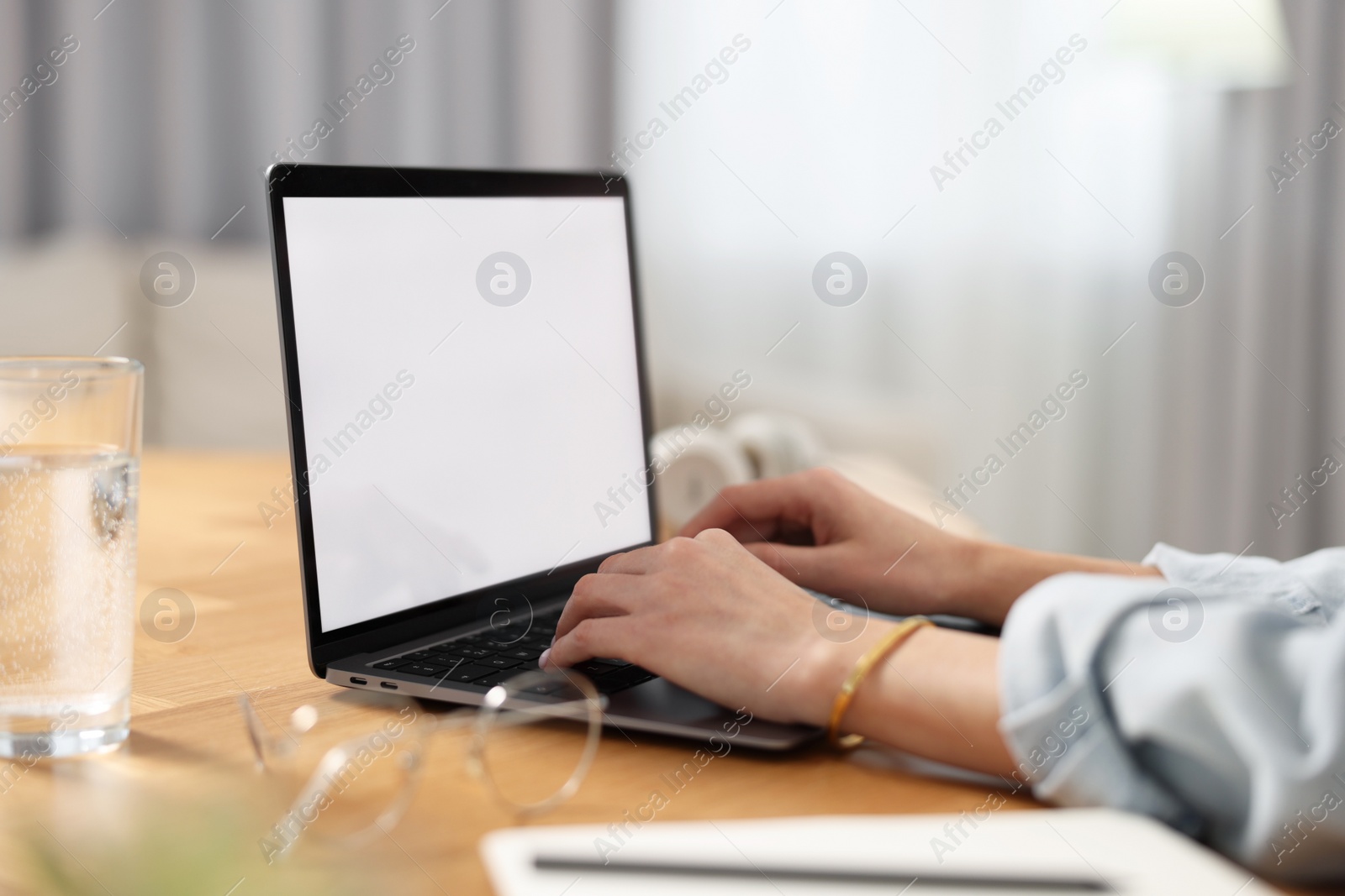 Photo of Young woman watching webinar at table in room, closeup