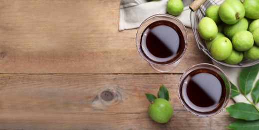 Image of Delicious liqueur and green walnuts on wooden table, flat lay with space for text. Banner design
