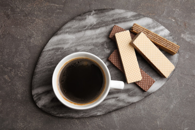 Delicious wafers and cup of coffee for breakfast on grey table, flat lay