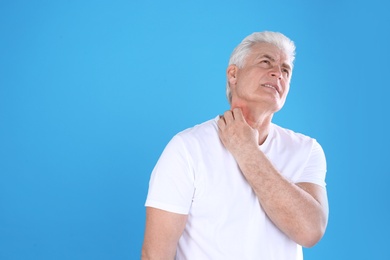 Photo of Senior man scratching neck on color background, space for text. Allergy symptom