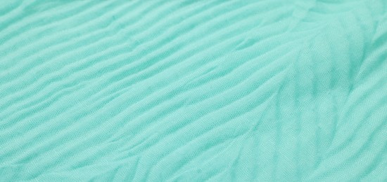 Texture of turquoise crumpled fabric as background, closeup