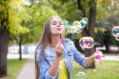 Photo of Young woman blowing soap bubbles in park