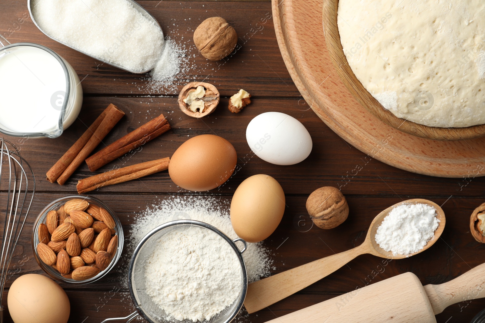 Photo of Dough and ingredients for pastries on wooden table, flat lay