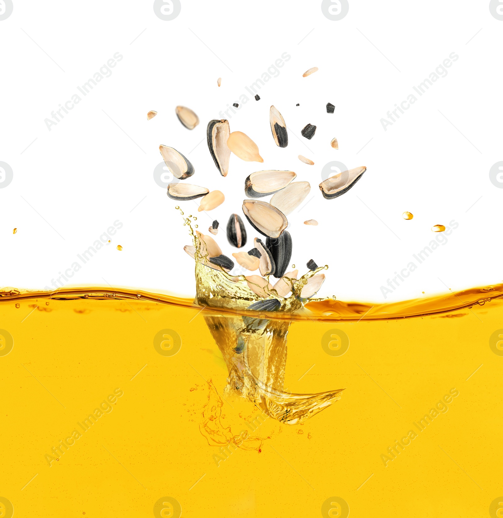 Image of Sunflower seeds falling into cooking oil on white background