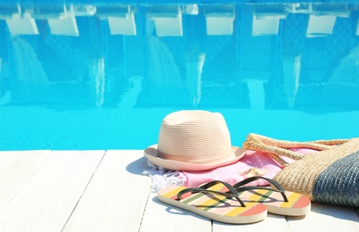 Photo of Beach accessories on wooden deck near swimming pool. Space for text