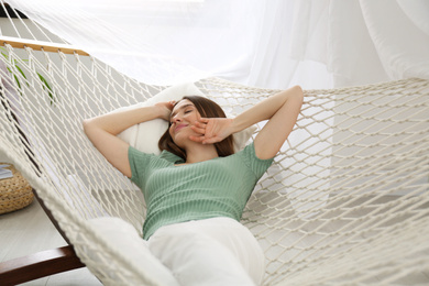 Happy woman lying in hammock at home