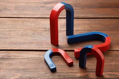 Red and blue horseshoe magnets on wooden background. Space for text