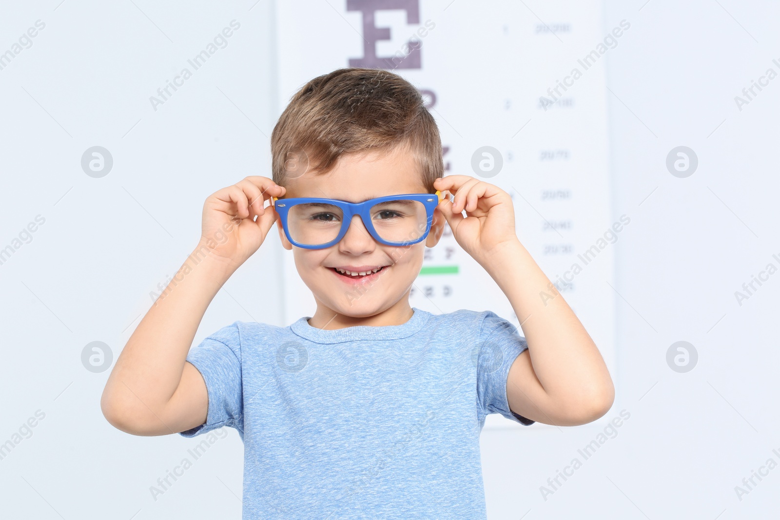 Photo of Little boy with glasses visiting children's doctor in clinic, space for text. Eye examination