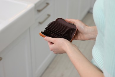 Woman with empty wallet at home, closeup
